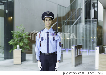 一名年輕的保全站在辦公大樓入口大廳。 122526542