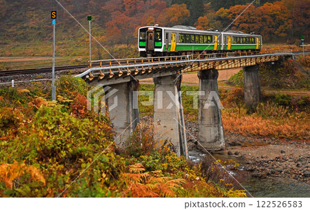 The Tadami Line running over the Gamou River Bridge with autumn leaves 122526583