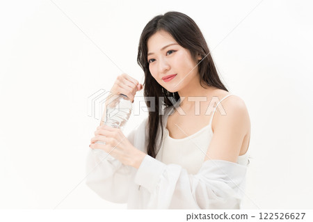 A young woman trying to open a plastic bottle A young woman trying to open a plastic bottle 122526627