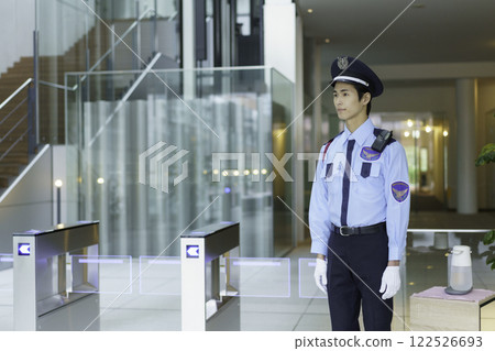 A young security guard standing at the entrance/exit gate of an office building. Photo courtesy of Sky Perfect Tokyo Media Center 122526693