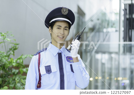 A young security guard talking on a walkie-talkie in an office building. Photo courtesy of Sky Perfect TV Tokyo Media Center 122527097
