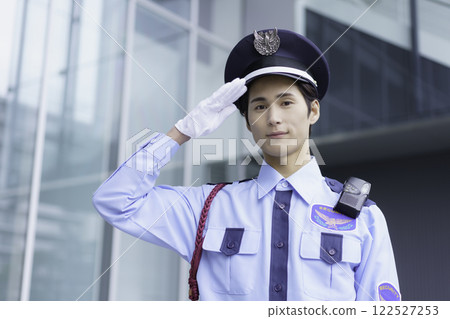 一名年輕保全在辦公大樓外站立敬禮。 一名年輕保全在辦公大樓外站立敬禮。 122527253