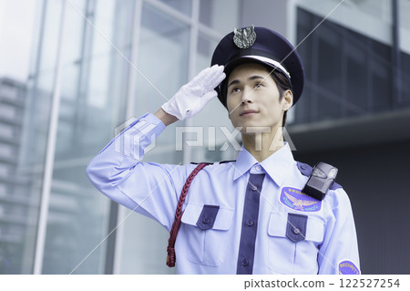 一名年輕保全在辦公大樓外站立敬禮。 122527254