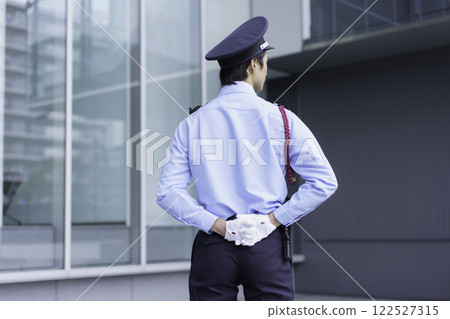The back view of a young security guard standing outside an office building. Photo courtesy of Sky Perfect Tokyo Media Center. 122527315