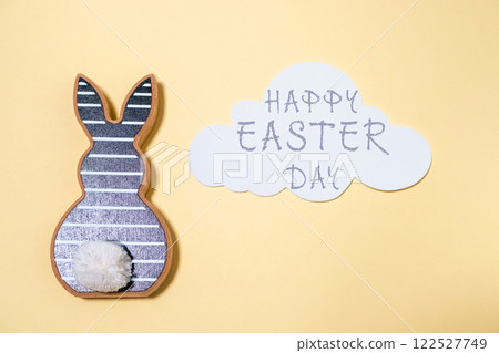 Rabbit is sitting on a yellow background with a cloud in the background 122527749