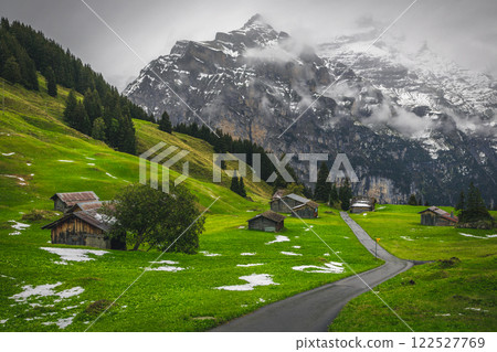 Scattered alpine wooden huts and misty snowy mountains in Switzerland Scattered alpine wooden huts and misty snowy mountains in Switzerland 122527769