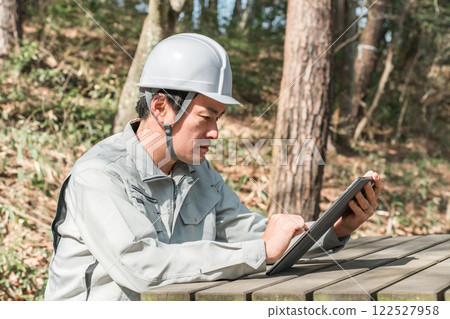 A male forestry and park maintenance worker checking a tablet 122527958