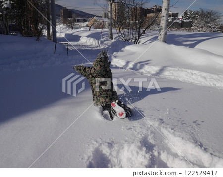 Child playing in the snow (back view) 122529412
