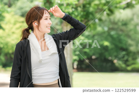 Woman running, walking, jogging, exercising (diet, sports) with earphones in the park 122529599