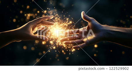 Two hands reaching for each other, exchanging golden magic light and particles 122529902