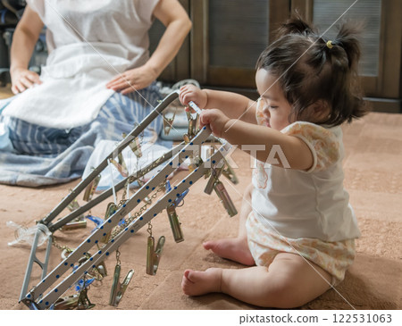 [Baby with twin tails touching a laundry hanger] 122531063