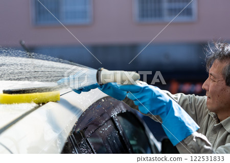 A man washing his car in his home parking lot 122531833