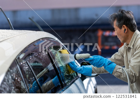A man washing his car in his home parking lot A man washing his car in his home parking lot 122531841