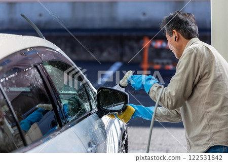 A man washing his car in his home parking lot A man washing his car in his home parking lot 122531842