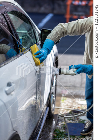 A man washing his car in his home parking lot A man washing his car in his home parking lot 122531845