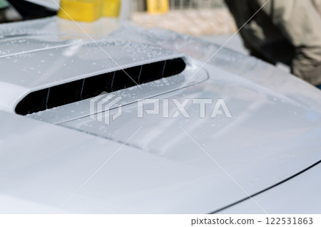 A man washing his car in his home parking lot A man washing his car in his home parking lot 122531863