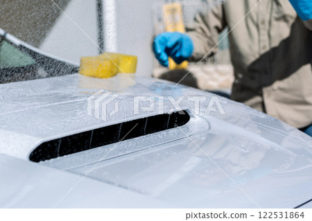 A man washing his car in his home parking lot A man washing his car in his home parking lot 122531864