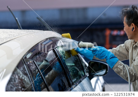 A man washing his car in his home parking lot A man washing his car in his home parking lot 122531974