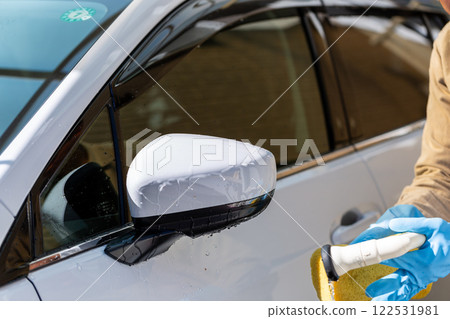 A man washing his car in his home parking lot 122531981