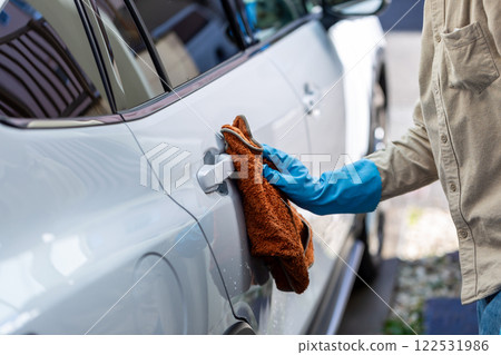 A man washing his car in his home parking lot A man washing his car in his home parking lot 122531986