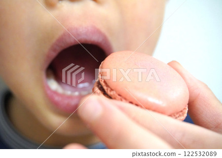 Child munching on macaron Child munching on macaron 122532089