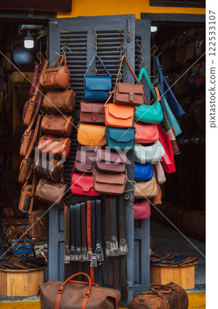 handmade leather bags, belts and accessories on counter in shop at street market in Hoi An in Vietnam in Asia 122533107