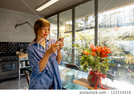 Woman Using Smartphone in a Bright Modern Kitchen 122533419