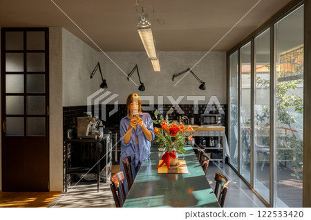 Woman Using Smartphone in a Stylish Modern Kitchen 122533420