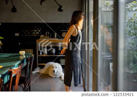 Woman Reflecting by the Window with Dog Nearby 122533421