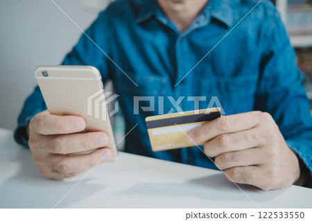 Close up male hands holding credit card and smartphone, shopping online, buying on internet. 122533550