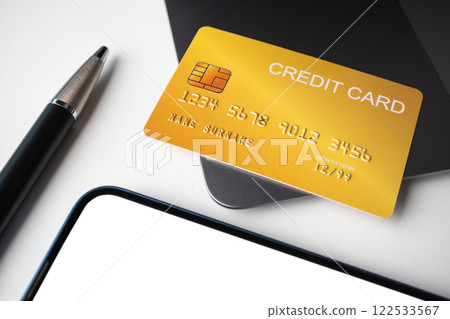 Credit card placed on laptop with pen and smartphone on white background. Cashless technology and credit card payment concept. 122533567