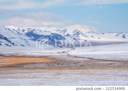 Long road through a snowy plateau to the mountains. 122534900