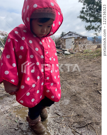 Girl wearing a pink poncho Girl wearing a pink poncho 122536323
