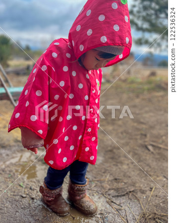 Girl wearing a pink poncho Girl wearing a pink poncho 122536324