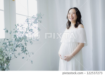 Pregnant woman standing by the window 122537273
