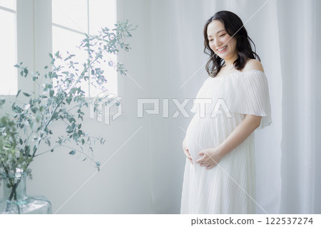 Pregnant woman standing by the window 122537274