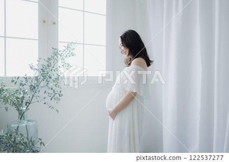 Pregnant woman standing by the window 122537277