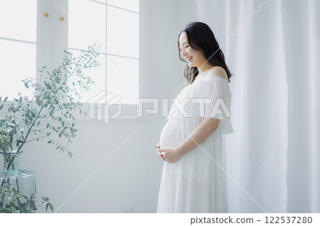 Pregnant woman standing by the window Pregnant woman standing by the window 122537280