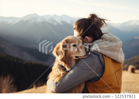 Man and his golden retriever dog, wearing a scarf, share a loving moment in a stunning mountain setting during their outdoor hike 122537921