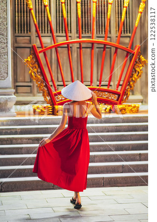 back of a young woman tourist in traditional Vietnamese hat Non La at a pagoda in Vietnam on travel to Asia 122538117