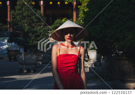 Portrait of female tourist in a Vietnamese traditional hat non la on pagoda in Vietnam in Asia 122538137