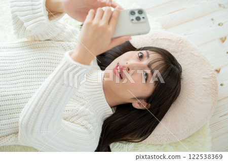 一名日本女性仰臥操作智慧型手機 一名日本女性仰臥操作智慧型手機 122538369