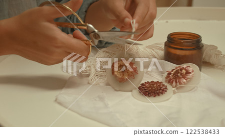 Cutting the string of a handmade soy wax scented candle embedded with a flower for a springtime theme craft, creative eco-friendly sustainable zero waste lifestyle 122538433