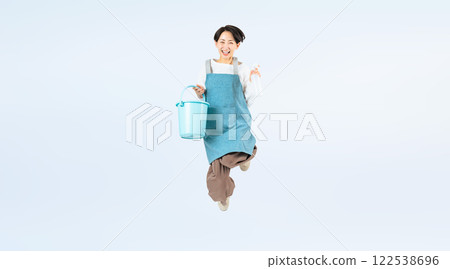一名中年婦女身穿圍裙拿著清潔工具跳躍的全身照片 一名中年婦女身穿圍裙拿著清潔工具跳躍的全身照片 122538696