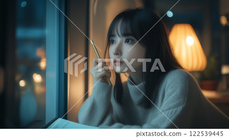 Pensive woman with pencil in hand in a night room 122539445