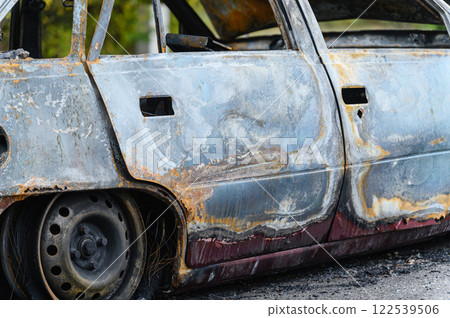 Burned car wreck abandoned on roadside in nature 122539506