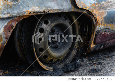 Close-up of burnt wheel. Black charred tire with wire cord. Close-up of burnt wheel. Black charred tire with wire cord. 122539509
