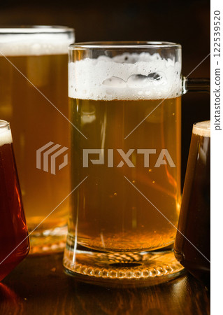 Variety of beer glasses with different types of beer on wooden table. Close-up. Variety of beer glasses with different types of beer on wooden table. Close-up. 122539520