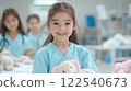 young girl in veterinarian scrubs smiles while caring for stuffed animal in playful clinic setting 122540673