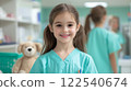smiling young girl in veterinarian scrubs stands in clinic setting, with stuffed animal in background 122540674